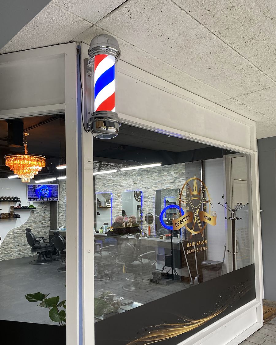 De winkel van De Goude Hand met de kapperspaal en het gouden logo op het raam